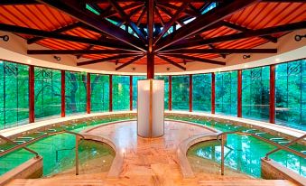 a large indoor pool surrounded by wooden beams , with a wooden floor and a ceiling covered in bamboo at Le Grand Hotel