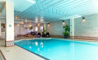 an indoor swimming pool surrounded by a spa area , with several chairs and tables placed around the pool at Rodd Grand Yarmouth