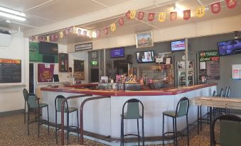 a bar area with a long counter , several stools , and a television mounted on the wall at Hotel Kerwick