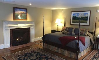 a cozy bedroom with a large bed , a fireplace , and a rug on the floor at Peter Allen Inn & Event Center