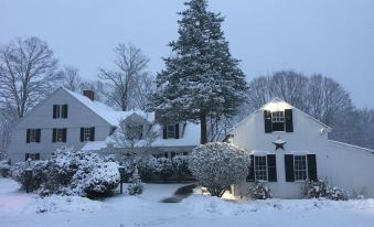 a snowy scene with a house covered in snow and a tree standing in the front yard at Spring Hill Inn