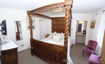 a large wooden bed with a canopy is in a room with white walls and a chandelier at The Old Rectory