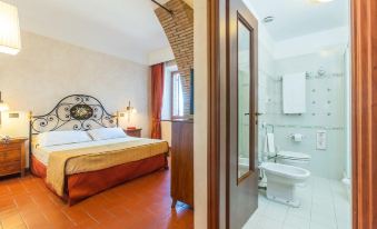 a bedroom with a bed and a bathroom with a toilet next to it , both situated in a room with a tiled floor at Hotel Ristorante la Pergola