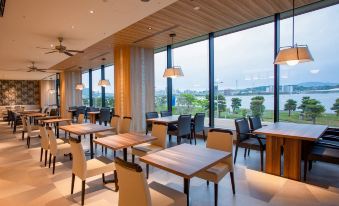 a modern restaurant with wooden tables and chairs , large windows , and a view of the city at Hotel Ichibata