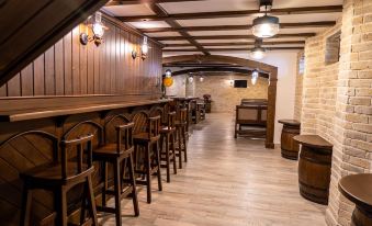 a bar area with wooden chairs and tables , as well as barrels lining the walls at Hotel Avenue - Avenue Hotels