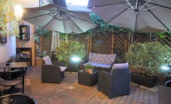 a well - lit outdoor seating area with umbrellas , chairs , and a fire pit , creating a cozy atmosphere at Hotel Del Corso