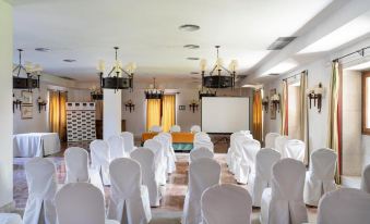 a conference room set up for a meeting , with chairs arranged in rows and a projector screen on the wall at Parador de Verin