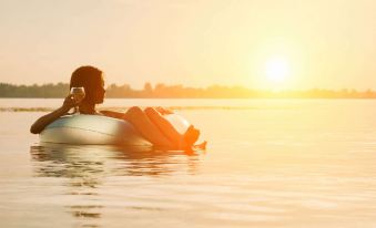 a woman is floating on an inner tube in a lake , enjoying the sunset while wearing a bikini at Thunderbird Motel Hillsboro
