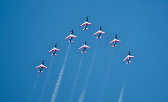 a group of airplanes in the sky with a clear blue sky and white smoke trails at AC Hotel Paris le Bourget Airport