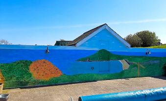 a large mural of a house with a pool is painted on the side of a building at Trenewydd Farm Holiday Cottages