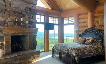 a bedroom with a large bed , stone fireplace , and a view of the mountains outside the window at Mont du Lac Resort