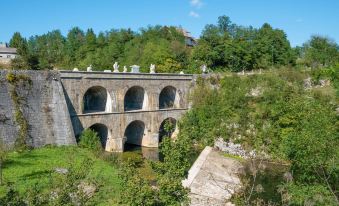 a stone bridge with arches is built into the side of a hill , surrounded by trees at Tina