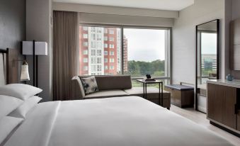 a hotel room with a large window offering a view of the city , a white bed , and a couch at Bethesda North Marriott Hotel & Conference Center