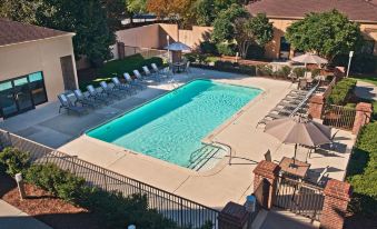 an outdoor swimming pool surrounded by lounge chairs and umbrellas , providing a relaxing atmosphere for guests at Sonesta Select Raleigh Durham Airport Morrisville