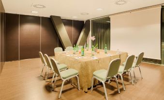 a conference room with a large table surrounded by chairs , and a green sign on the wall at NH Orio Al Serio