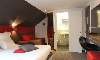 a hotel room with a red and white bed , a brown couch , and an open door leading to a bathroom at Best Western the Hotel Versailles