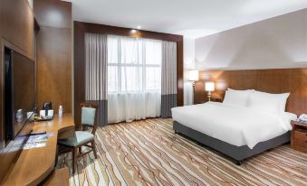 a hotel room with a large bed , a desk , and a window , all decorated in a modern style at Radisson Blu Hotel Buraidah