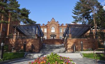 a brick building with a large flower garden in front of it , surrounded by trees at Hotel Parus