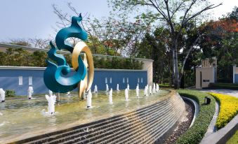 a large sculpture of a dragon is surrounded by smaller sculptures and set on a stone wall in a park at RK Riverside Resort & Spa (Reon Kruewal)