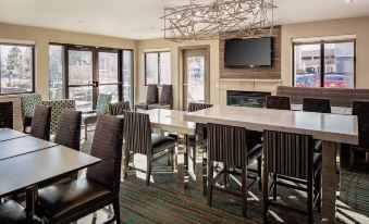a modern dining room with wooden chairs and tables , a fireplace , and a tv on the wall at Residence Inn Denver Tech Center