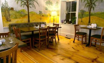 a dining room with wooden floors , a table with chairs , and a mural on the wall at The Birchwood Inn