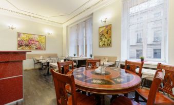 a dining room with wooden tables and chairs arranged around them , creating a cozy atmosphere at Alexander Hotel