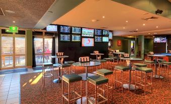 a modern bar with multiple tvs , seating areas , and drinks , as well as an adjacent restaurant at Prince of Wales Hotel