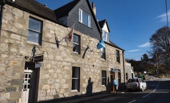 a building with two flags hanging from it , one of which is the scottish flag at The Kirkmichael Hotel