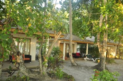 a tropical beach house surrounded by lush greenery , with several chairs placed around the area at Vilamendhoo Island Resort & Spa