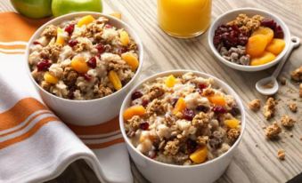 a wooden table with two bowls of cereal , one with berries and the other with nuts , placed next to each other at Home2 Suites by Hilton Dekalb