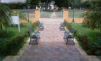 a paved walkway surrounded by benches and a gate , with a red arrow pointing to the right at Hostal la Casona