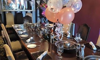 a long dining table set up for a birthday celebration , adorned with balloons and confetti at The Blue Bell Inn