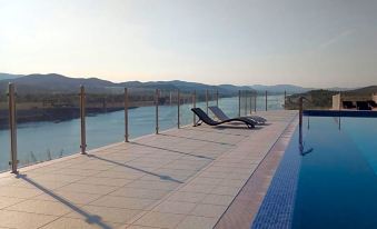 a large pool with a glass railing overlooks a body of water and mountains in the background at Hotel Panorama