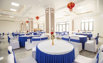 a large banquet hall with multiple round tables covered in blue tablecloths , creating a festive atmosphere at Doan Gia Resort Phong Nha