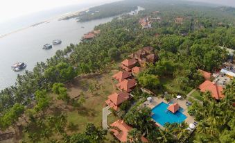 aerial view of a resort with multiple buildings and a swimming pool surrounded by lush greenery at Poovar Island Resort