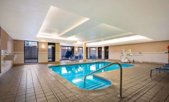 an indoor swimming pool with a diving board and chairs , surrounded by a brick wall at Sonesta Select Detroit Novi