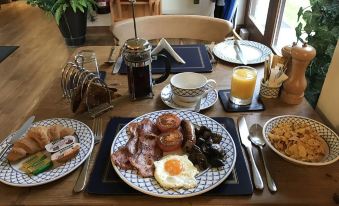a table is set with a plate of breakfast items , including bacon , eggs , and toast at Church Farm Lodge