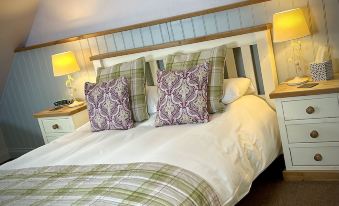 a cozy bedroom with a white bed , green and white bedding , and two nightstands on either side of the bed at Sibton White Horse Inn