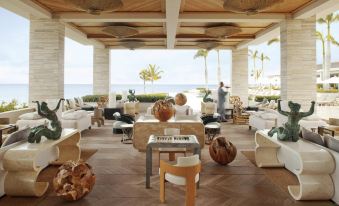 a man standing near a dining table in a room with a view of the ocean at Four Seasons Resort and Residence Anguilla