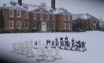 a large white and black chess set is displayed in front of a red brick house at Chilston Park Hotel