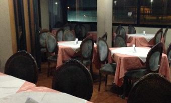 a restaurant with multiple dining tables and chairs , some of which are covered in white tablecloths at Hotel Miramar