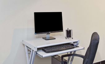 a white desk with a computer monitor , keyboard , and mouse is set up on a desk at Knights Inn Pine Brook