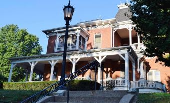 a large , two - story brick house with a white porch and steps leading up to it at Condotels