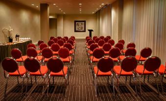 a large conference room with rows of red chairs arranged in an orderly fashion , ready for a meeting or event at Hotel Manoir Victoria