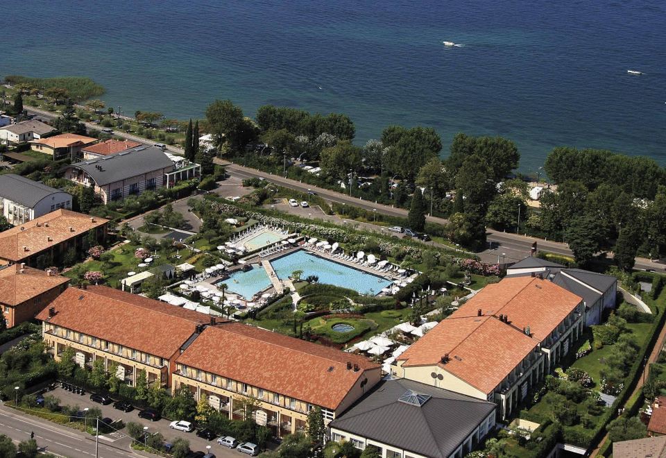 a large resort with a pool and multiple buildings , surrounded by trees and the ocean at Hotel Caesius Thermae & Spa Resort