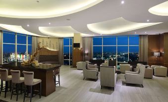a modern lounge area with a large window offering a view of the city at night at Galaxy Hotel Banjarmasin