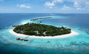 aerial view of a tropical island surrounded by clear blue water , with a bridge connecting to a small island in the distance at Joali Maldives