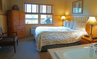 a bedroom with a large bed , nightstands , and a window , along with a bathroom nearby at Sugar Lake Lodge
