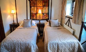 a cozy bedroom with two beds , each covered in white linens and topped with matching pillows at Thames Head Inn