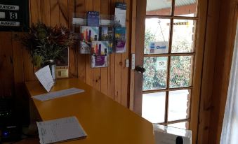 a wooden reception desk with a window , signs , and a vase of flowers in front of it at Country Road Motel St Arnaud